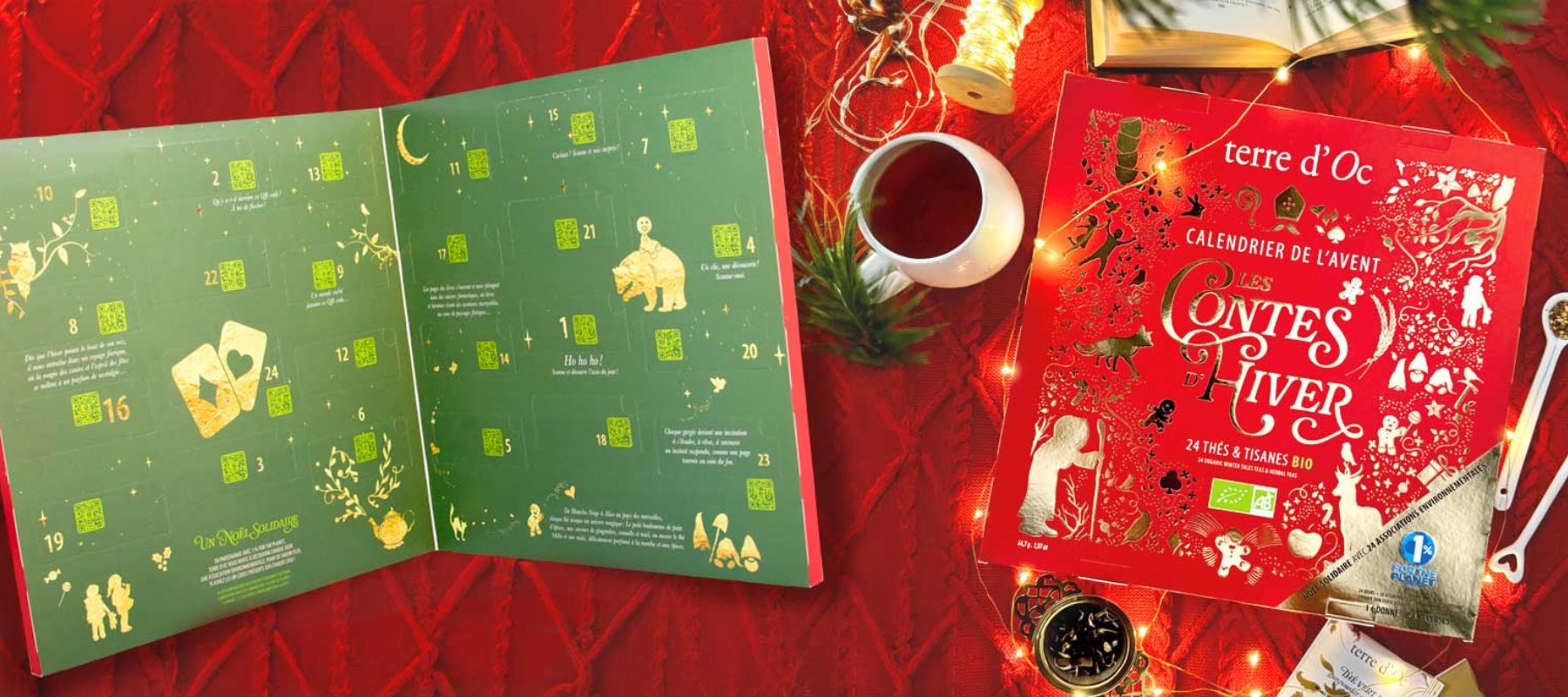 terre d’Oc tea Advent calendar, open to numbered compartments, beside its red-and-gold cover, a cup of tea and fairy lights.